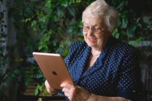 Elderly happy woman making video call online on modern tablet
