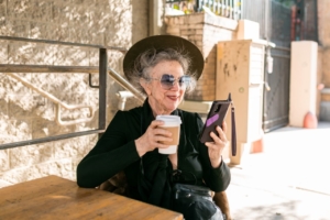 Woman in black using her smartphone while having coffee