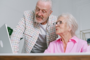Elderly couple with eyeglasses talking in front of a laptop