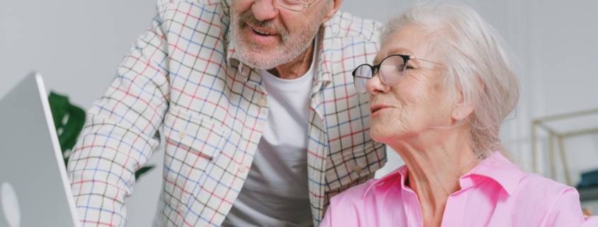 Elderly couple with eyeglasses talking in front of a laptop