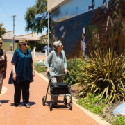 Elderly woman walking with a walker looking at a mural
