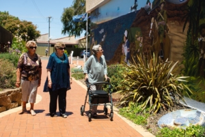 Elderly woman walking with a walker looking at a mural