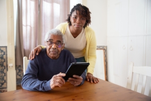 A woman standing beside an older man holding a tablet