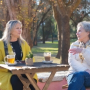 Two older women sitting at the park while having a conversation